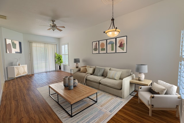 living area featuring dark wood-style floors, baseboards, and a ceiling fan