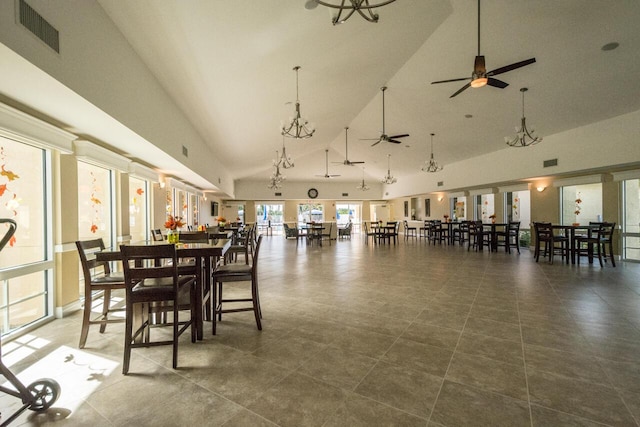 dining space with ceiling fan with notable chandelier, visible vents, and high vaulted ceiling