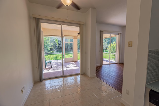 doorway with ceiling fan, light tile patterned flooring, and baseboards