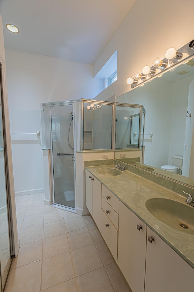 bathroom with double vanity, toilet, a stall shower, a sink, and tile patterned flooring