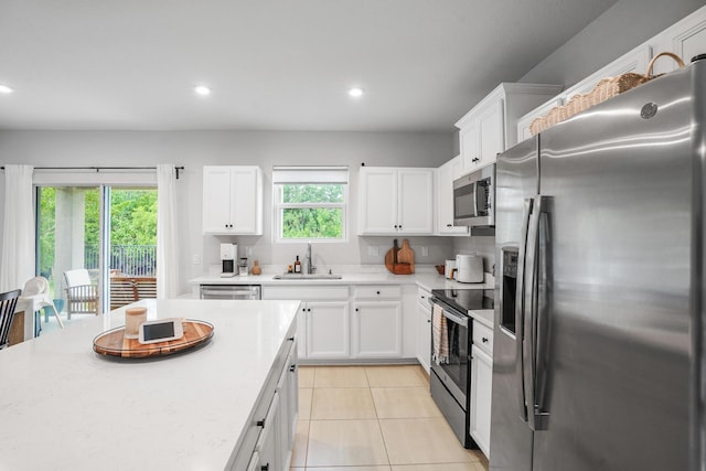 3625 Sapphire Hollow Way, Fort Pierce, FL 34981 - kitchen featuring light tile patterned floors, a sink, white cabinets, light countertops, and appliances with stainless steel finishes
