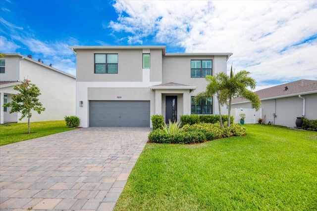 view of front of home with a front yard, decorative driveway, fence, an attached garage, and stucco siding