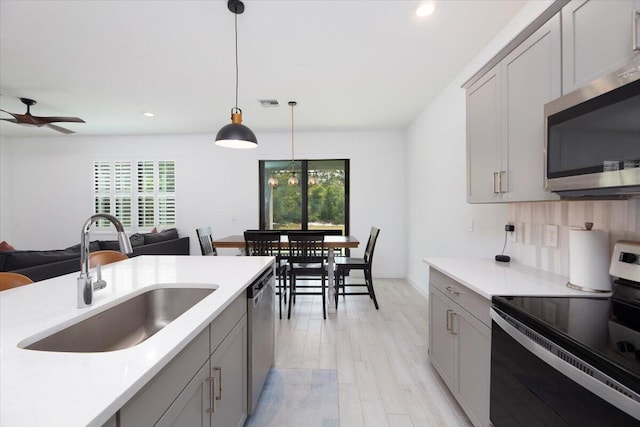 kitchen with gray cabinets, light wood-type flooring, a sink, stainless steel appliances, and recessed lighting