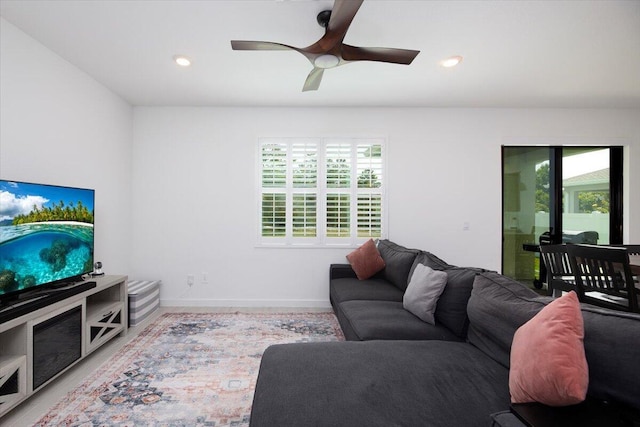 living room with baseboards, ceiling fan, and a wealth of natural light