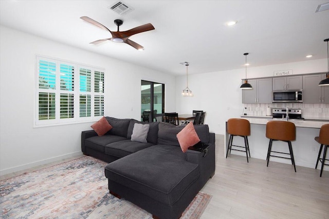 living room featuring a ceiling fan, visible vents, recessed lighting, and light wood finished floors