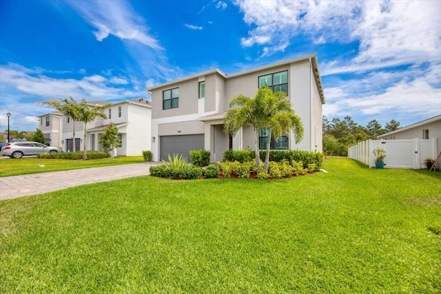 traditional-style home with a front lawn, fence, decorative driveway, stucco siding, and an attached garage