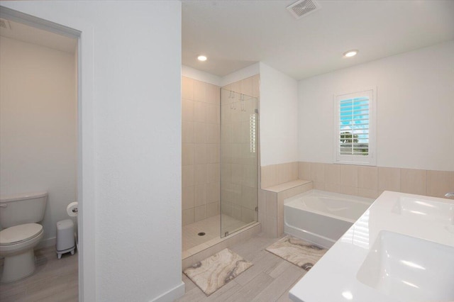 bathroom with toilet, a shower stall, wood finished floors, visible vents, and a bath