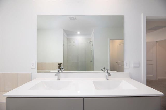 full bath with a sink, a shower stall, double vanity, and visible vents