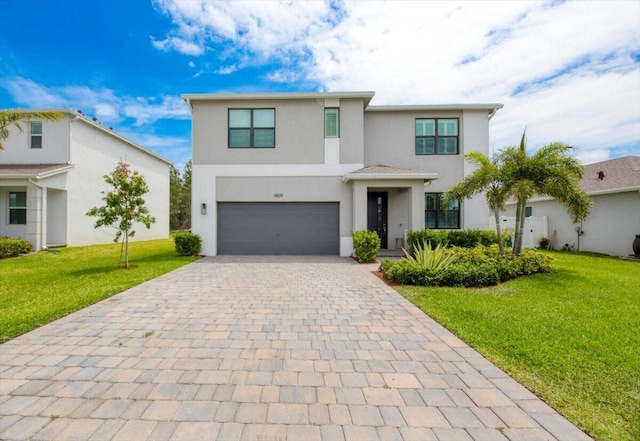view of front of house with an attached garage, decorative driveway, stucco siding, and a front yard