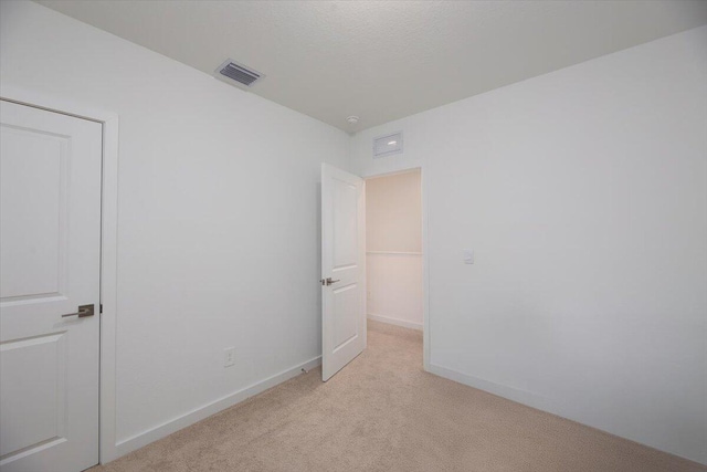 unfurnished bedroom with baseboards, visible vents, and light carpet