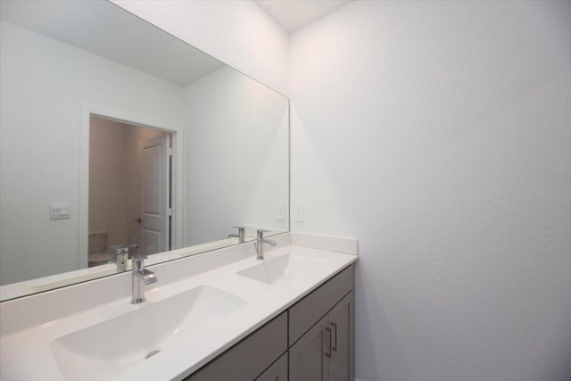 bathroom with double vanity, toilet, and a sink