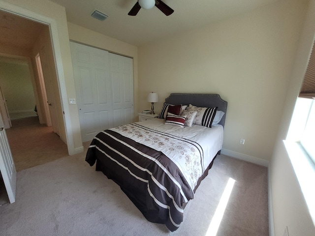bedroom featuring a ceiling fan, visible vents, light colored carpet, baseboards, and a closet