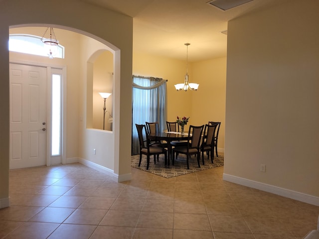 tiled foyer entrance featuring arched walkways, baseboards, and a notable chandelier