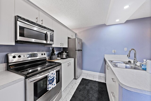 kitchen featuring light countertops, a sink, marble finish floor, and stainless steel appliances