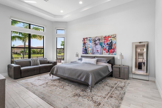 bedroom with recessed lighting, baseboards, light wood-style flooring, and a towering ceiling
