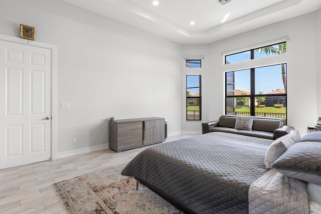 bedroom featuring visible vents, baseboards, light wood finished floors, a tray ceiling, and recessed lighting
