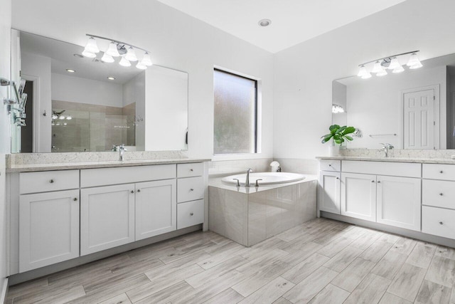 bathroom with two vanities, a sink, a bath, and a stall shower