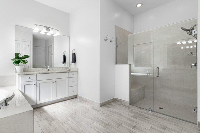 bathroom featuring vanity, wood finished floors, baseboards, recessed lighting, and a stall shower