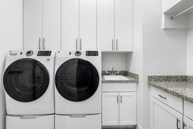 washroom featuring a sink, cabinet space, and independent washer and dryer