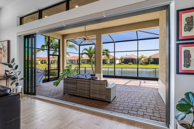 living area with a residential view, a ceiling fan, a water view, and wood finished floors