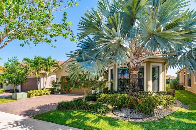 view of front of house with an attached garage, decorative driveway, and stucco siding