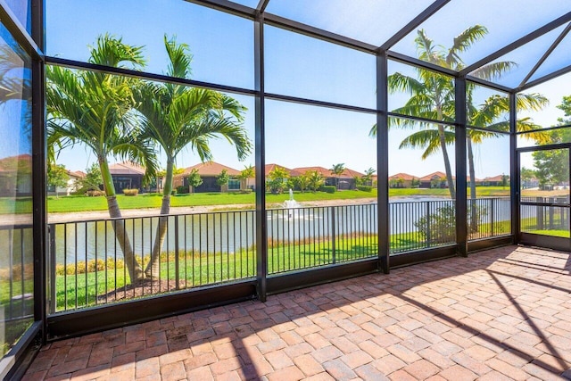 unfurnished sunroom featuring a water view and a residential view
