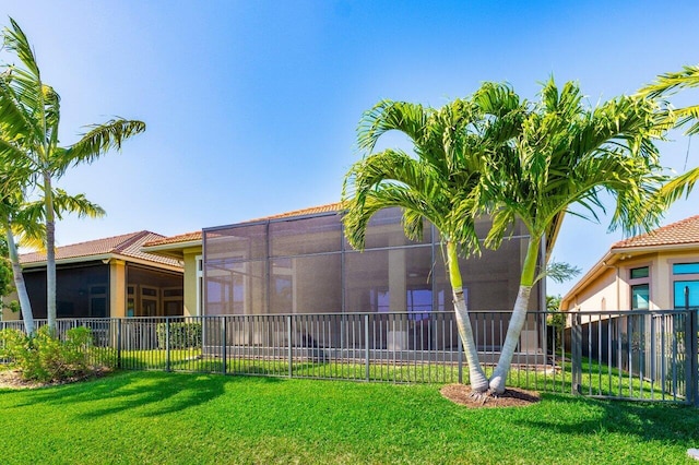 rear view of property featuring fence, a tiled roof, a yard, and stucco siding
