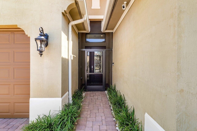 entrance to property featuring a garage and stucco siding