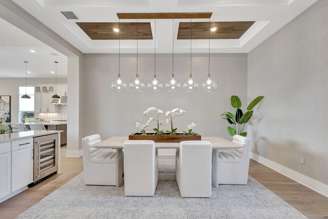 dining room featuring visible vents, beverage cooler, baseboards, light wood-type flooring, and a tray ceiling