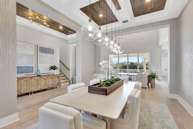 dining room with visible vents, stairway, a raised ceiling, baseboards, and light wood-style flooring