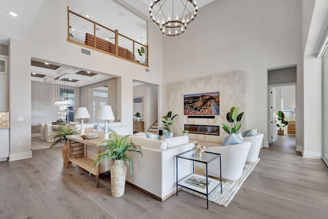 living area featuring light wood-style floors, a towering ceiling, and a notable chandelier