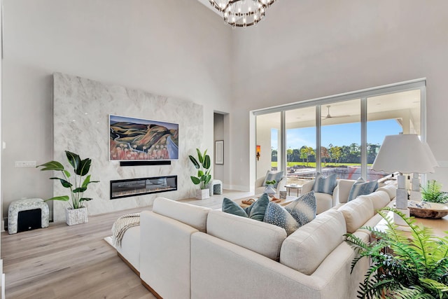 living area featuring an inviting chandelier, a high ceiling, a fireplace, and wood finished floors