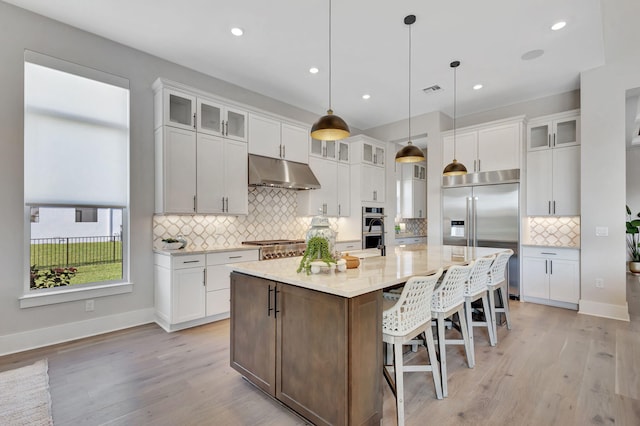 kitchen featuring under cabinet range hood, backsplash, appliances with stainless steel finishes, and white cabinetry