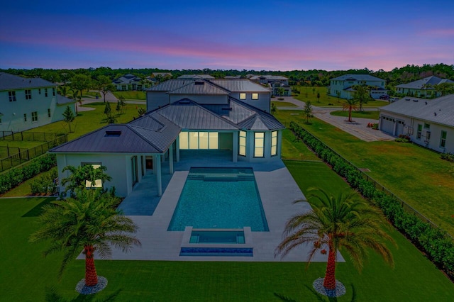 back of property at dusk featuring a patio area, metal roof, a residential view, and a standing seam roof