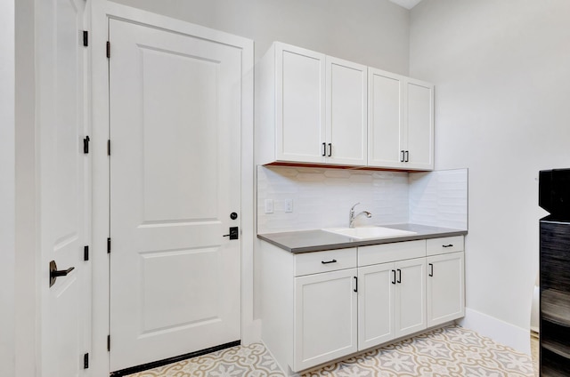 laundry area with baseboards, a sink, and light tile patterned floors