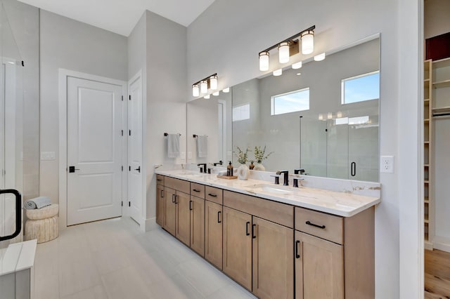 bathroom with a sink, baseboards, a shower stall, and double vanity
