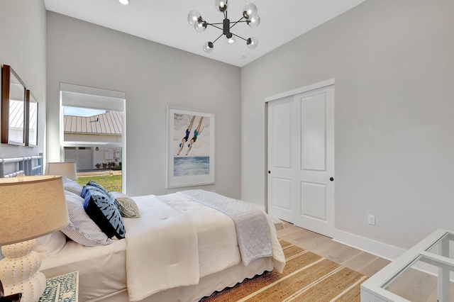 bedroom with light wood-type flooring, baseboards, and a notable chandelier