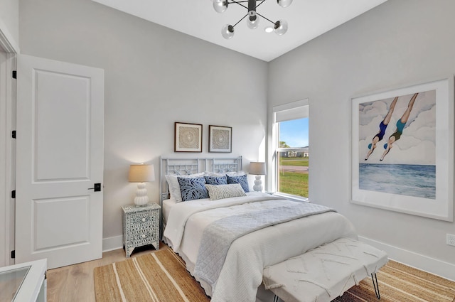 bedroom featuring baseboards, a notable chandelier, and light wood-type flooring