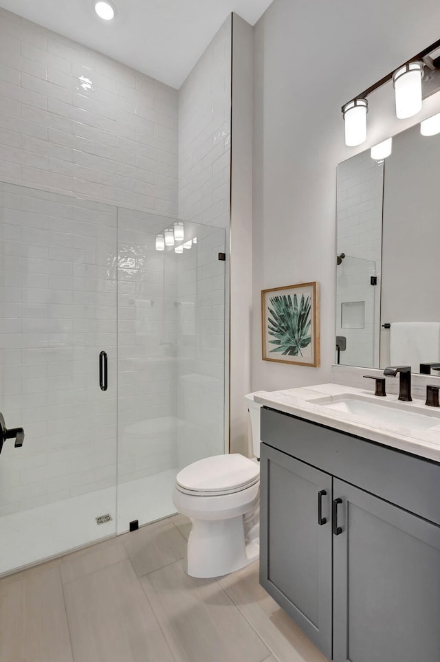 bathroom featuring vanity, recessed lighting, toilet, and a shower stall