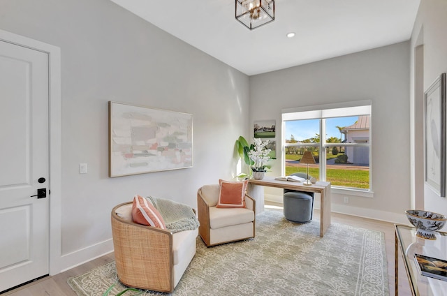 sitting room with baseboards, a chandelier, and wood finished floors