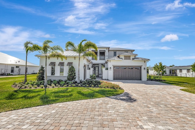view of front of house featuring a front yard, a garage, decorative driveway, fence, and stucco siding