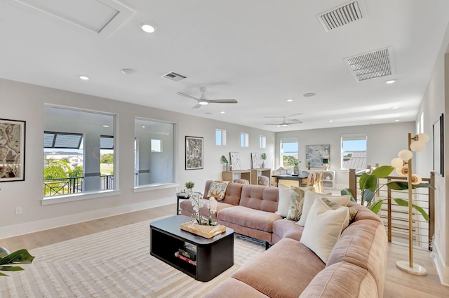 living area featuring visible vents, light wood-style floors, and baseboards