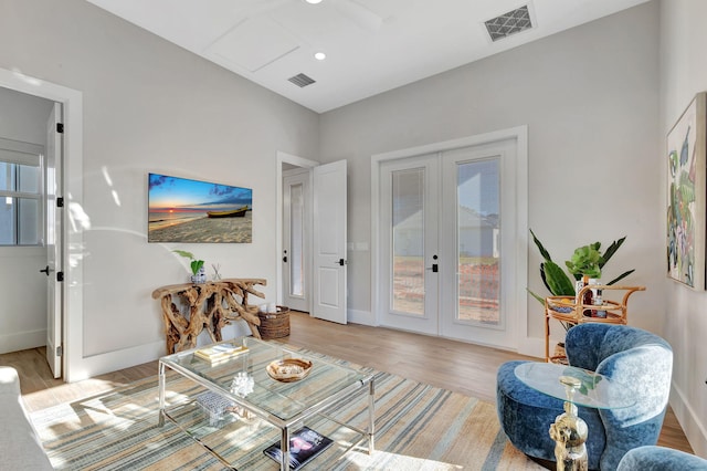 living room with light wood-style floors, french doors, and visible vents