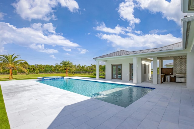 view of pool featuring area for grilling, french doors, exterior kitchen, a pool with connected hot tub, and a patio