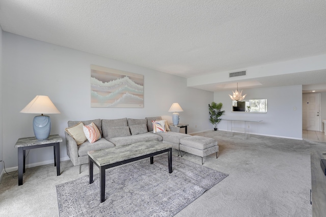 living area with visible vents, baseboards, a textured ceiling, carpet flooring, and a notable chandelier