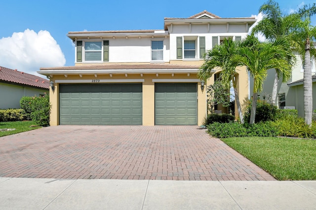 view of front facade featuring an attached garage, decorative driveway, and stucco siding