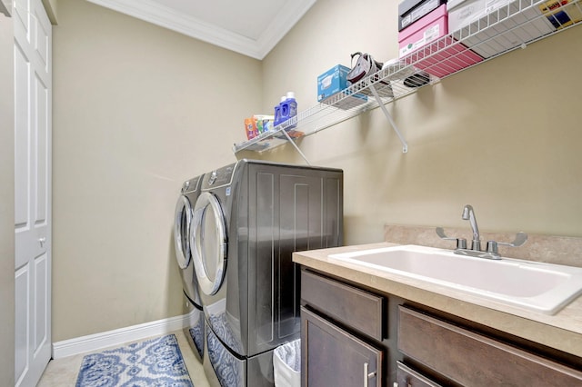 clothes washing area with crown molding, cabinet space, a sink, baseboards, and washer and dryer