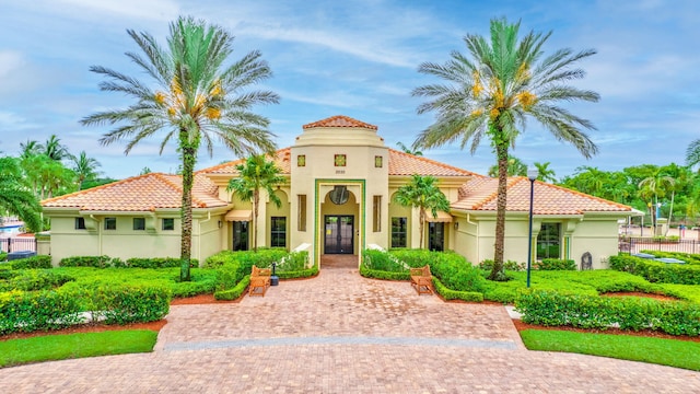 view of front of home featuring a tiled roof, fence, french doors, and stucco siding