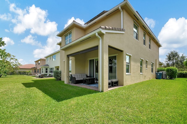 rear view of house featuring a lawn, stucco siding, an outdoor living space, and a patio area