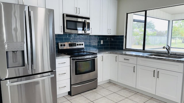 1942 SE Carvalho St, Port Saint Lucie, FL 34983 - kitchen with tasteful backsplash, a sink, light tile patterned floors, dark stone countertops, and stainless steel appliances